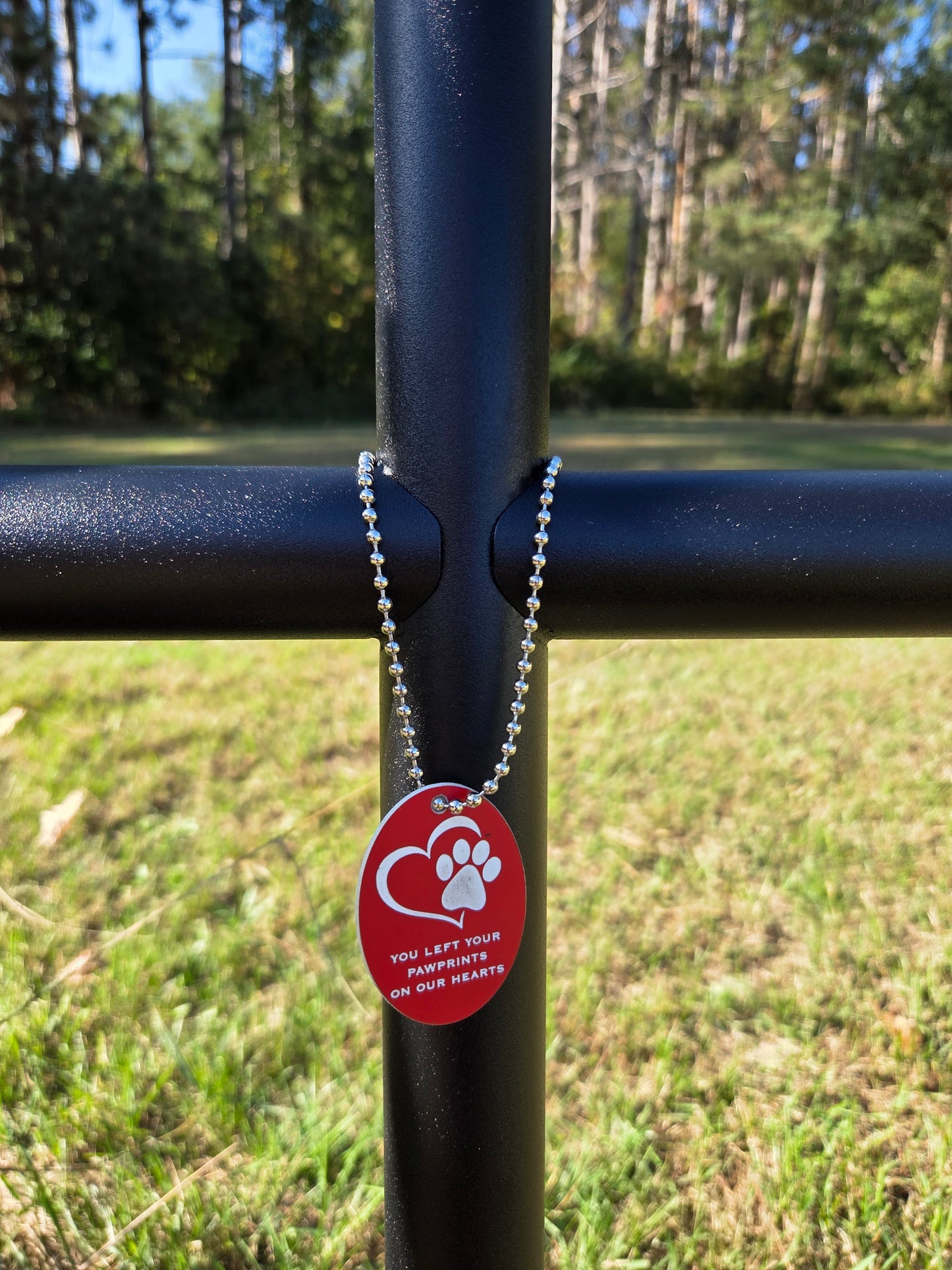 Everlasting Cross celebrating the loss of a fur baby with red EC Angle Charm with a heart and paw.  Is elegantly placed on memorial Black Ebony.