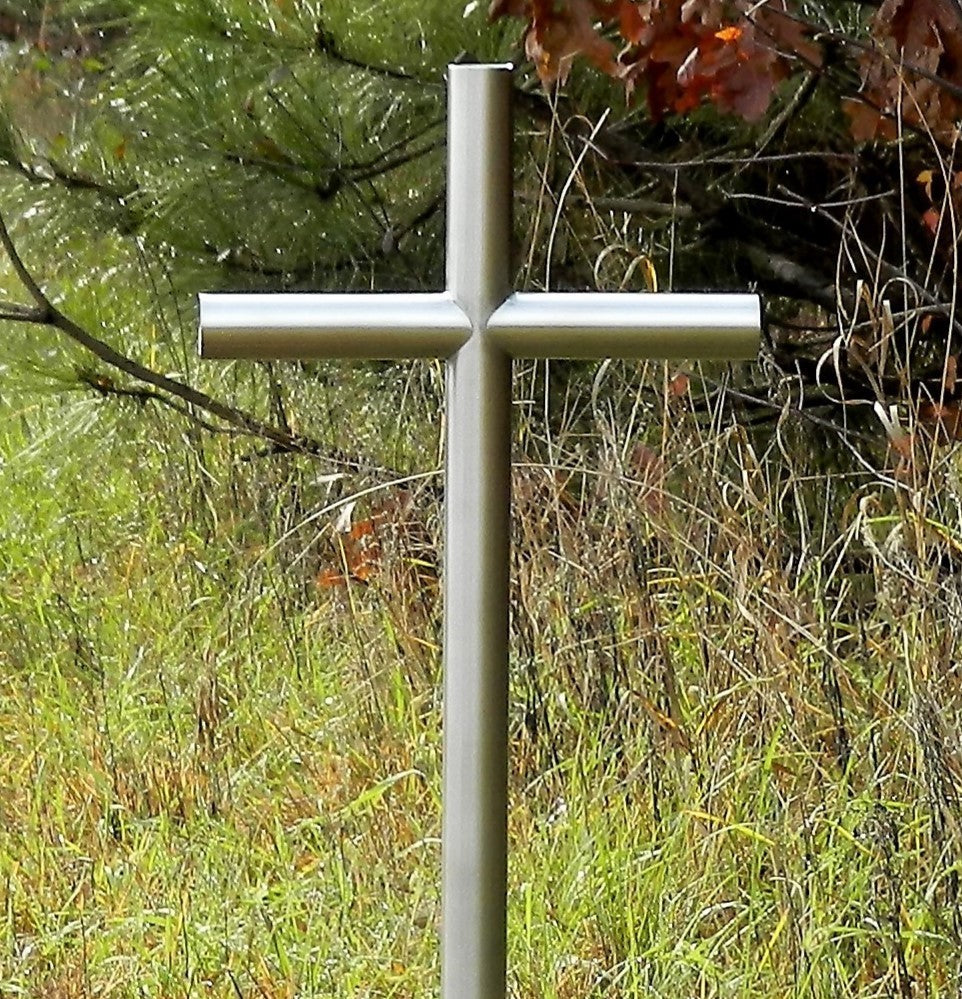Everlasting Cross™ Classic Satin Stainless Steel Finish Is place along side a group of pine trees as a final resting place.  Showing open end caps and no personalized engraving. It Symbolize A Loved One, At A Time of Lose To Help Heal and Preserve Our Memories.