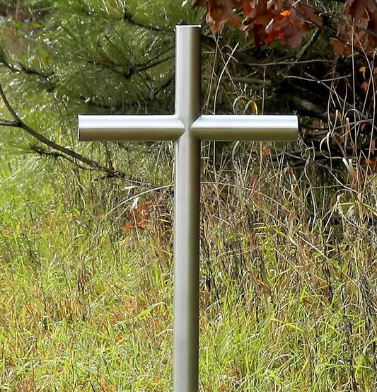 Everlasting Cross™ Classic Satin Stainless Steel Finish Is place along side a group of pine trees as a final resting place.  Showing open end caps and no personalized engraving. It Symbolize A Loved One, At A Time of Lose To Help Heal and Preserve Our Memories.