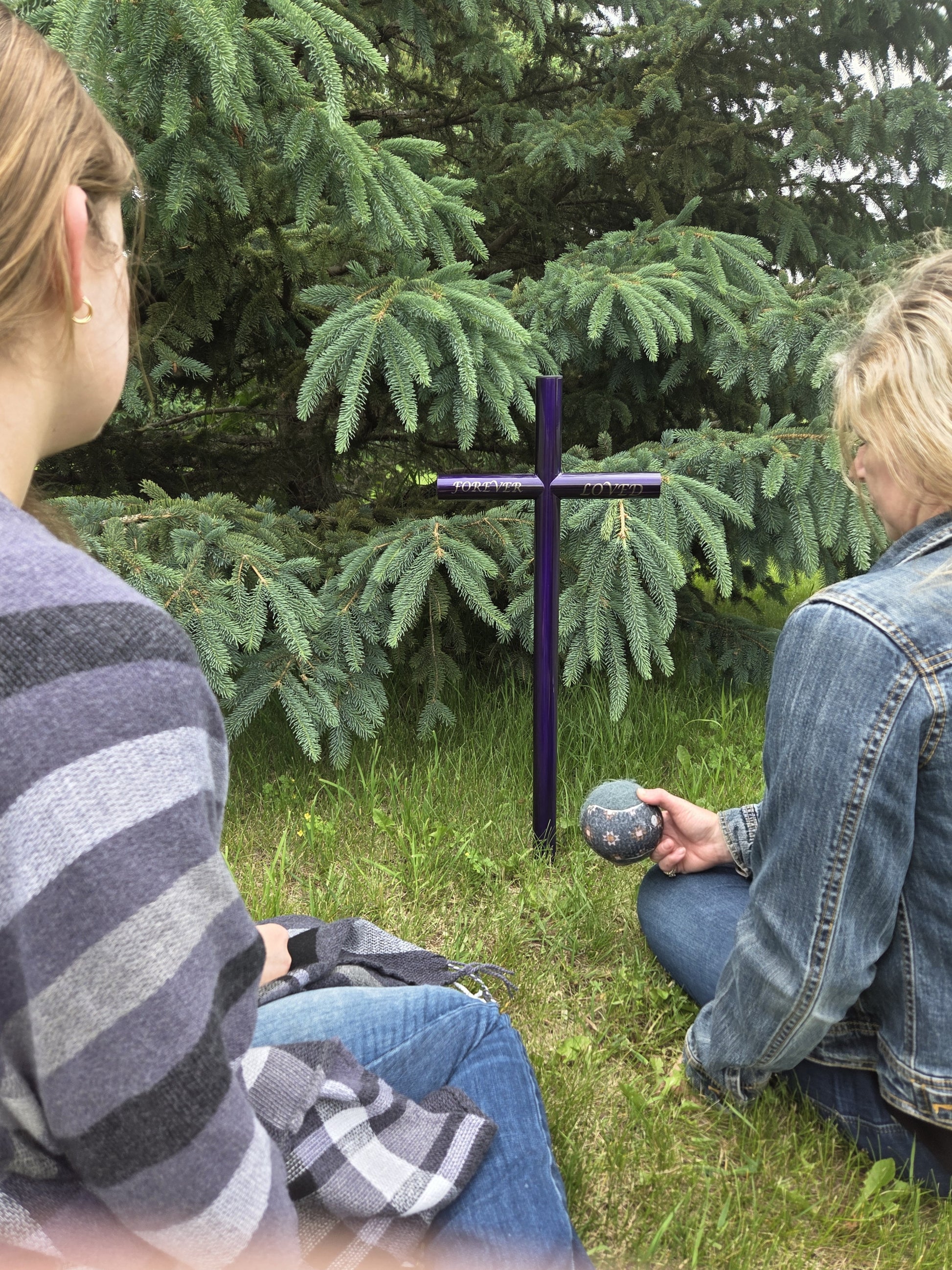 Two individuals remembering their loss of a pet.  Everlasting Cross in a size small, finished in an Amethyst purple and customized engraving.  Installed next to an Evergreen tree.